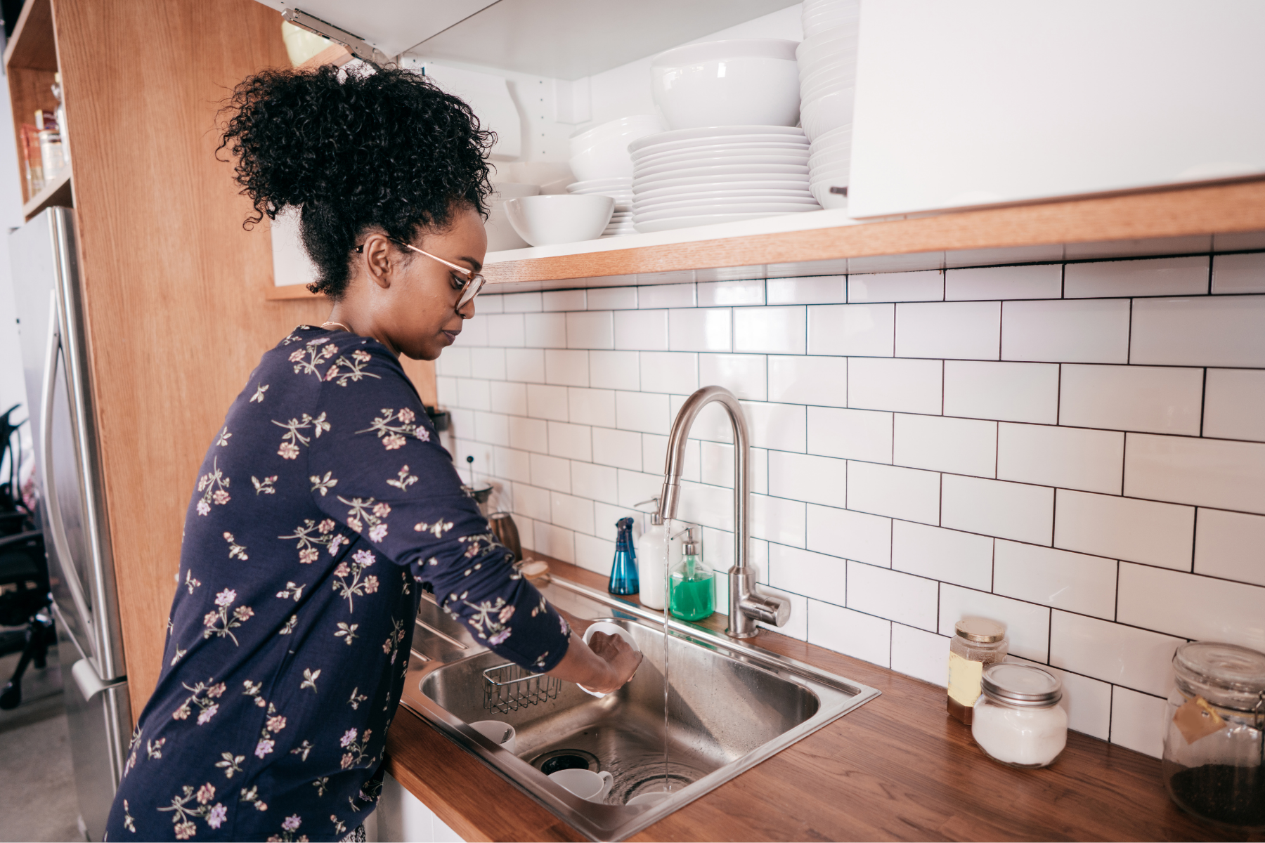 Female washing a cup in the kitchen sink